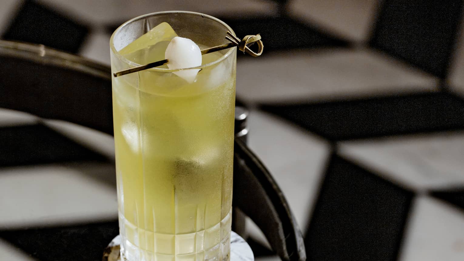 A yellow cocktail on a glass table.