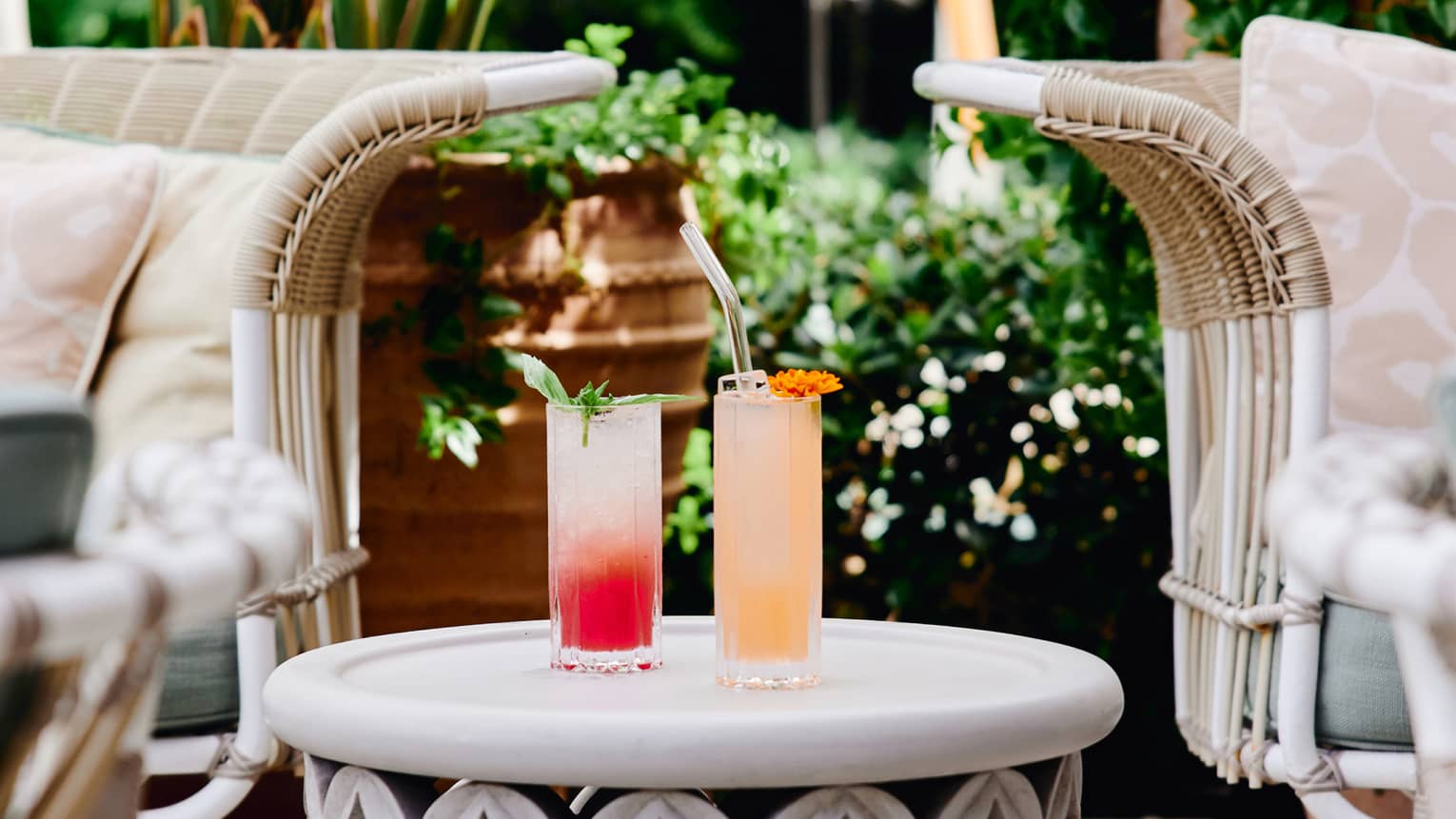 A red and orange cocktail on a small table outside.