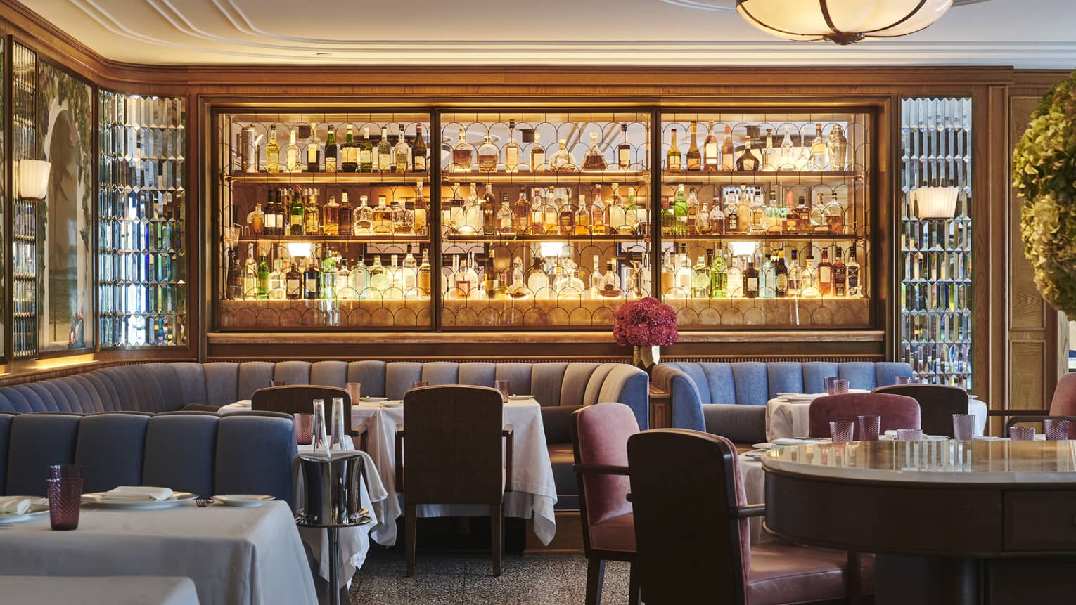 Fine dining restaurant with a stocked bar, upholstered seating, tables set with white tablecloths and warm ambient lighting