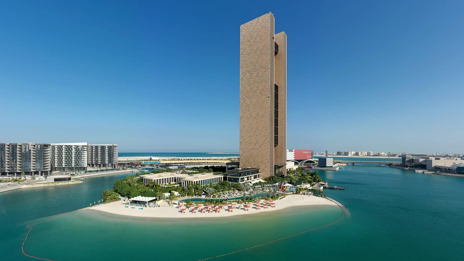 A drone shot of the outer facade of the resort, situated on an island with dark blue water surrounding.
