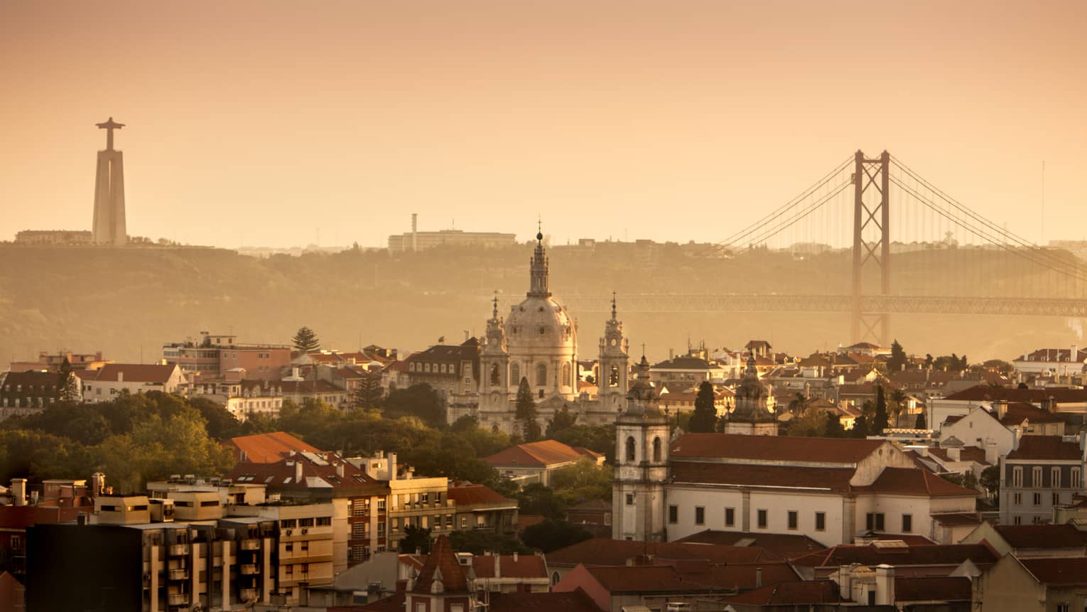Orange haze over Lisbon buildings, skyline and bridge at sunset