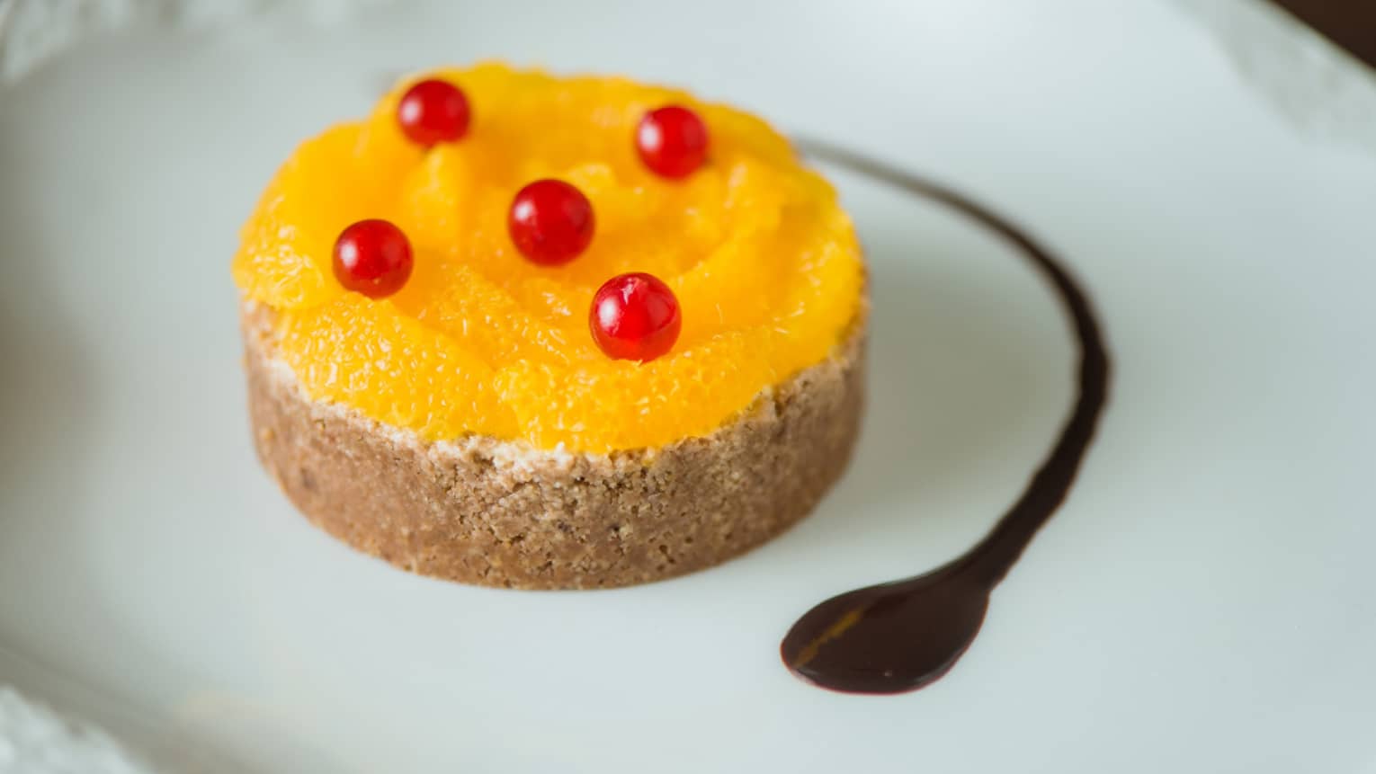 A small orange tart with tiny red berries on top.