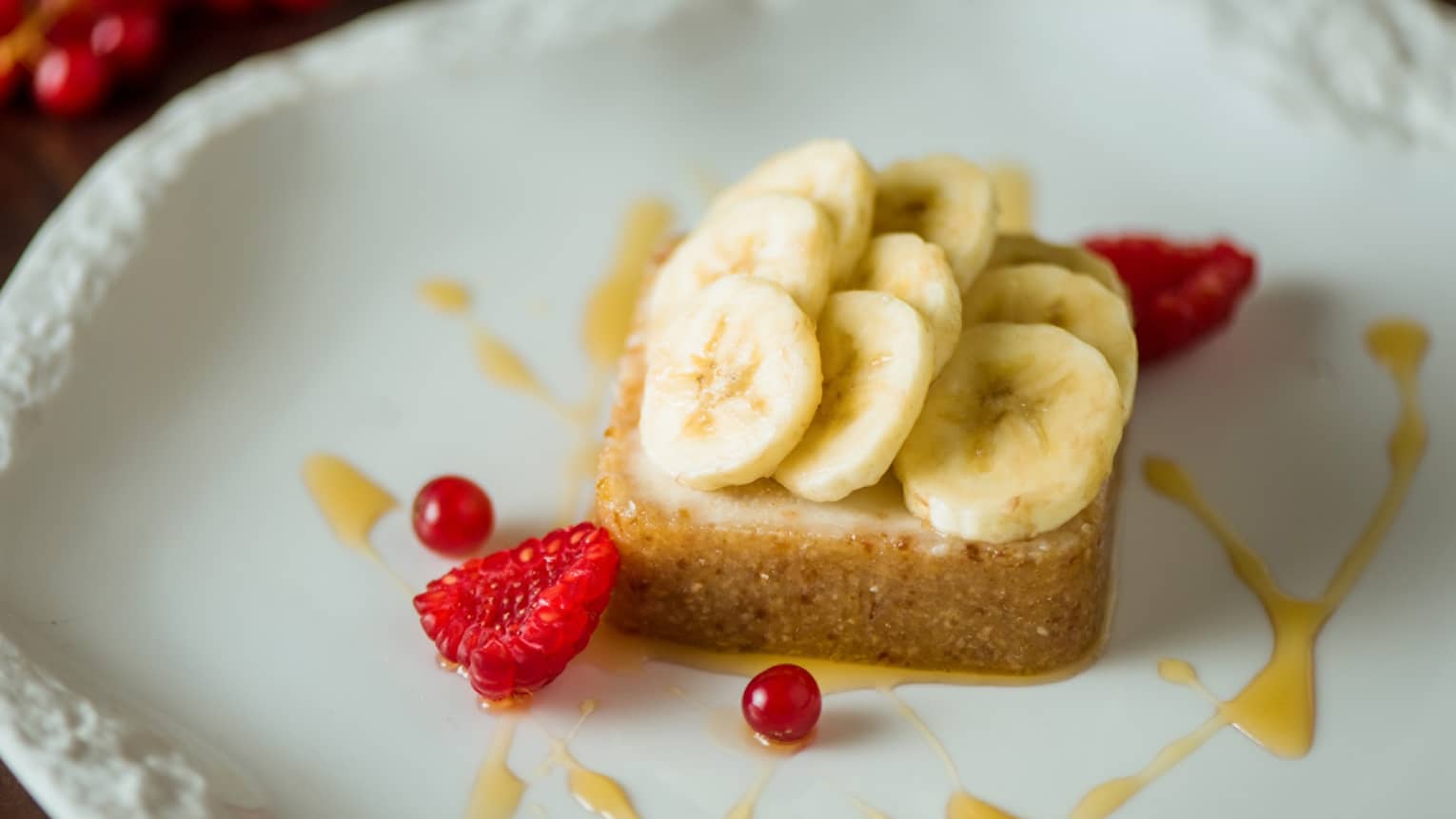 A slice of pie topped with banana and orange sauce.