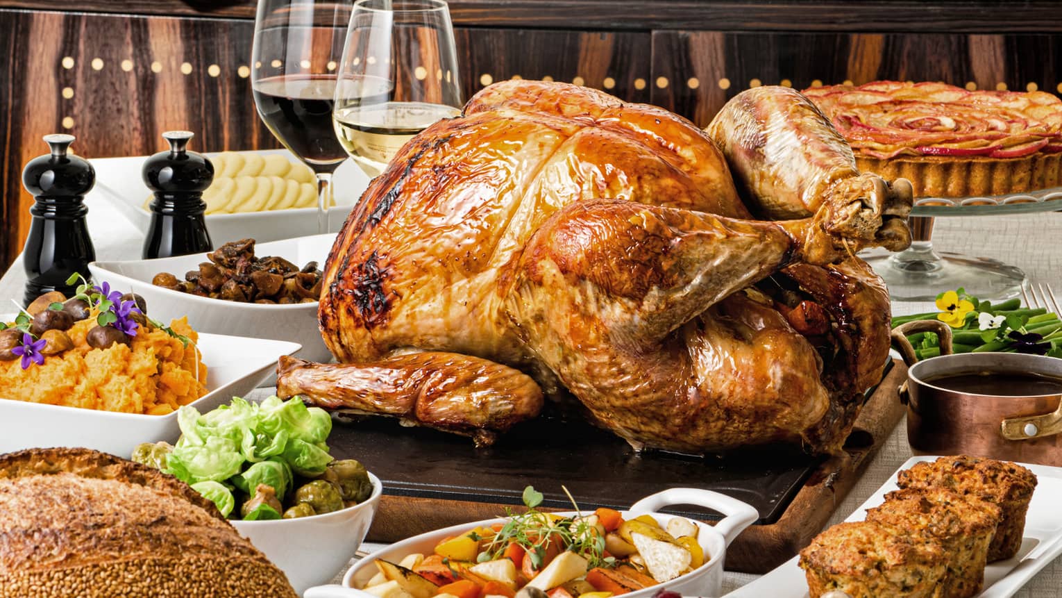 Thanksgiving food on trays such as turkey, breading, wine, stuffing, and pie.