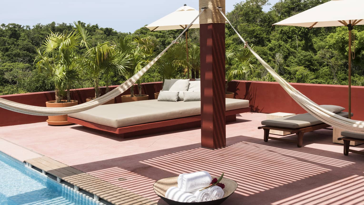 Pool terrace with red wood pergola and hanging hammocks