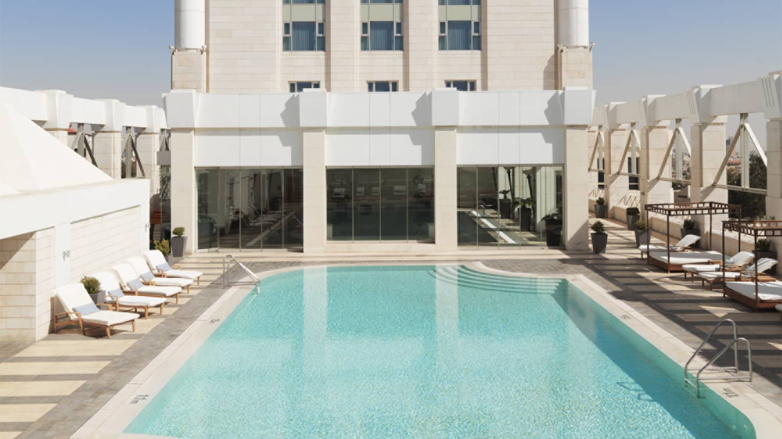 Aerial view of tall white building with blue swimming pool on sunny day