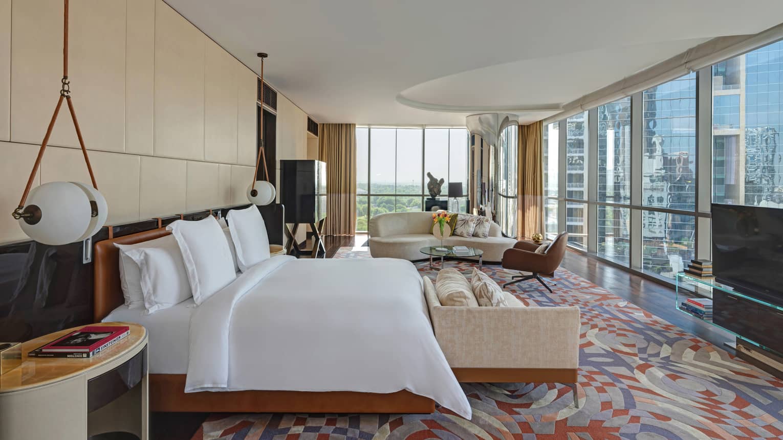 Bedroom with colorful rug, king bed, hanging beside lamps, sitting area