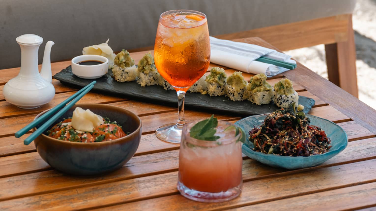 Sushi rolls with dipping sauce and drink in wine glass.