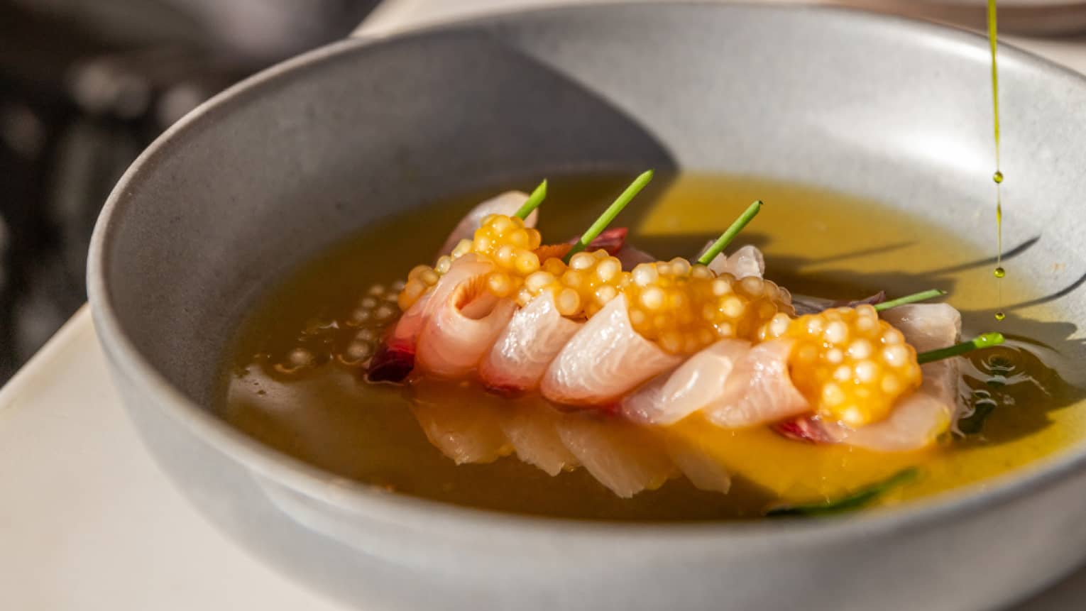 A person eating a bowl of tuna crudo