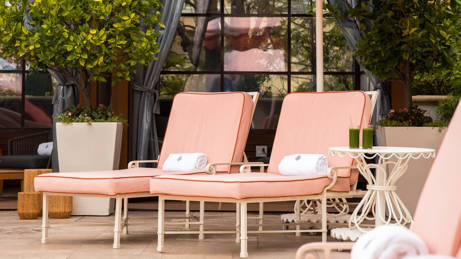 Pink lounge chair set beneath a pink scalloped-edge umbrella next to a row of poolside cabanas