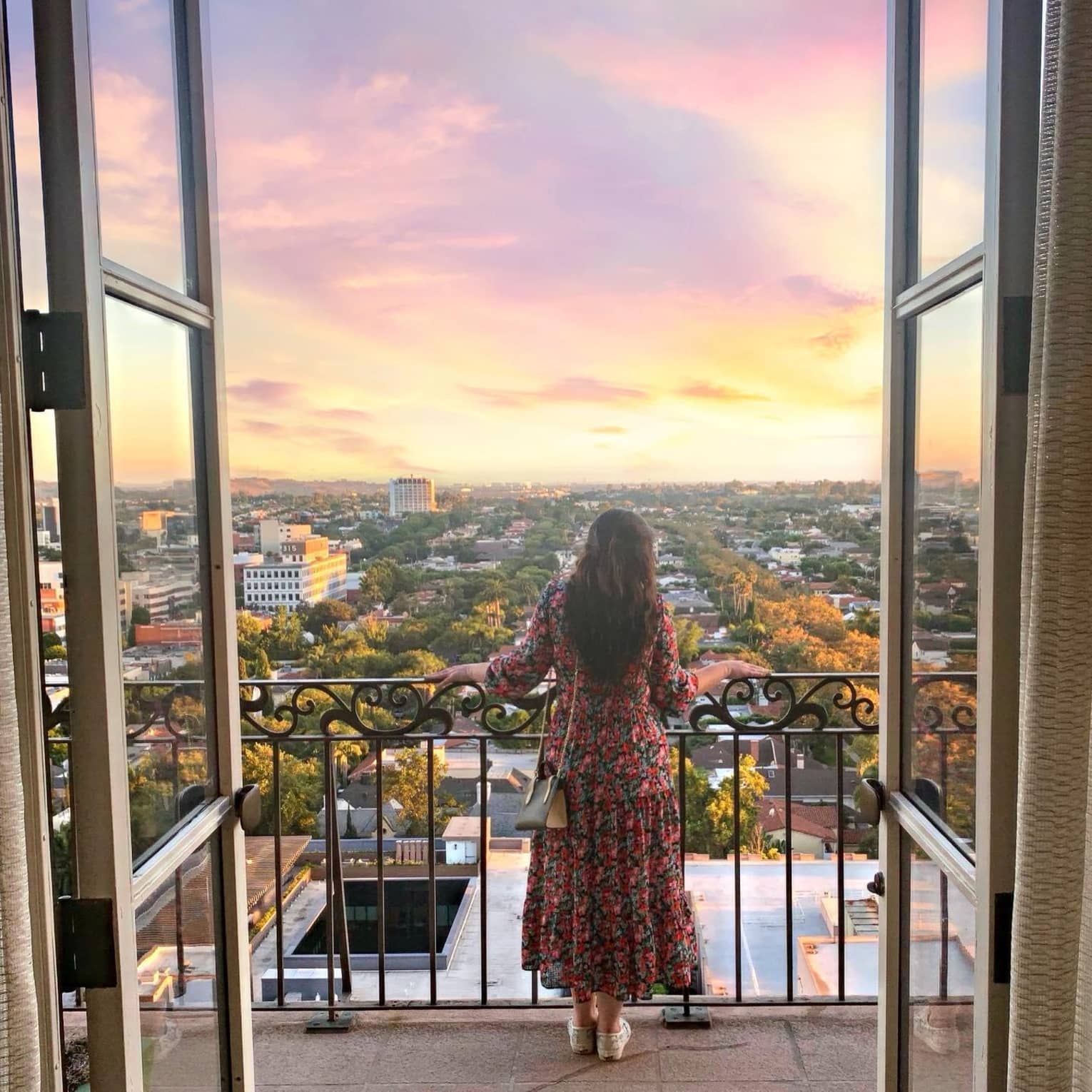 A woman standing on a balcony at sun set.