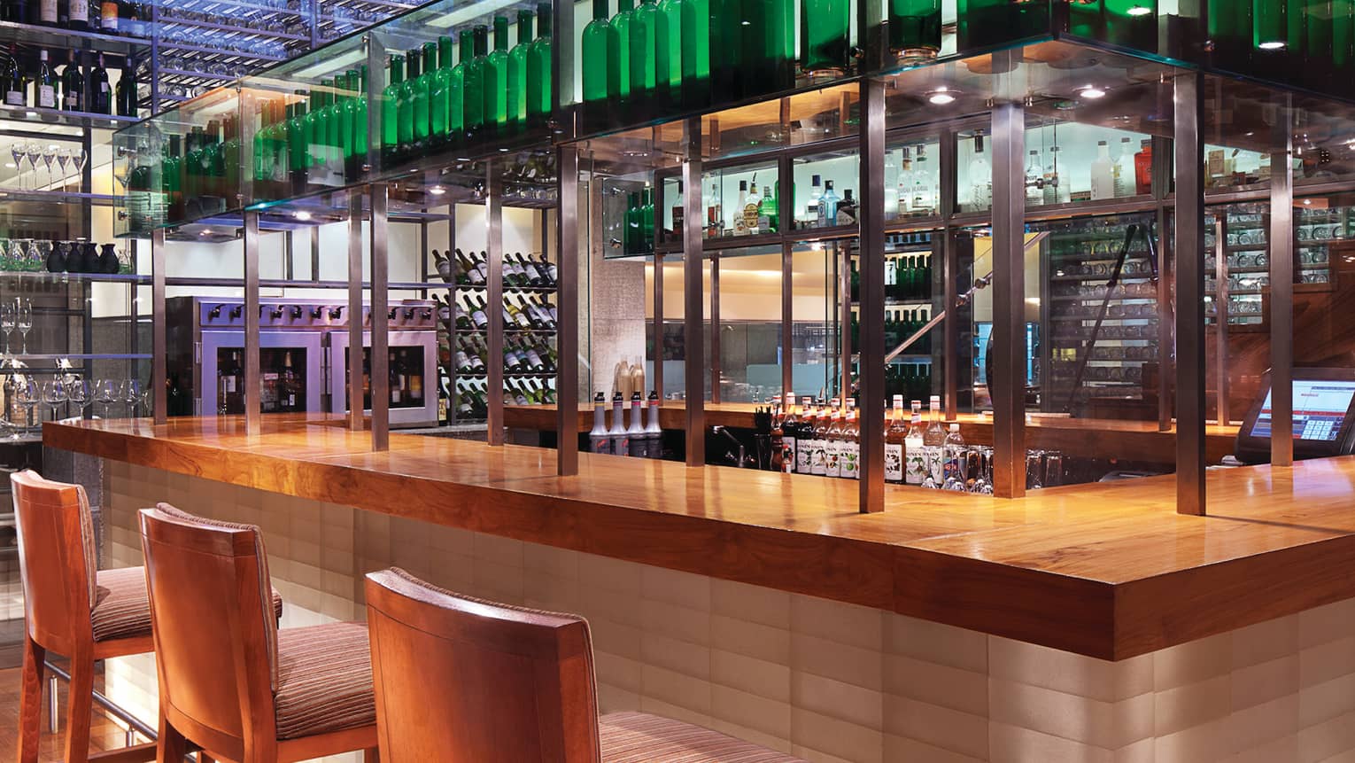 San Qi stools line modern wood bar with steel poles, shelves with wine bottles 