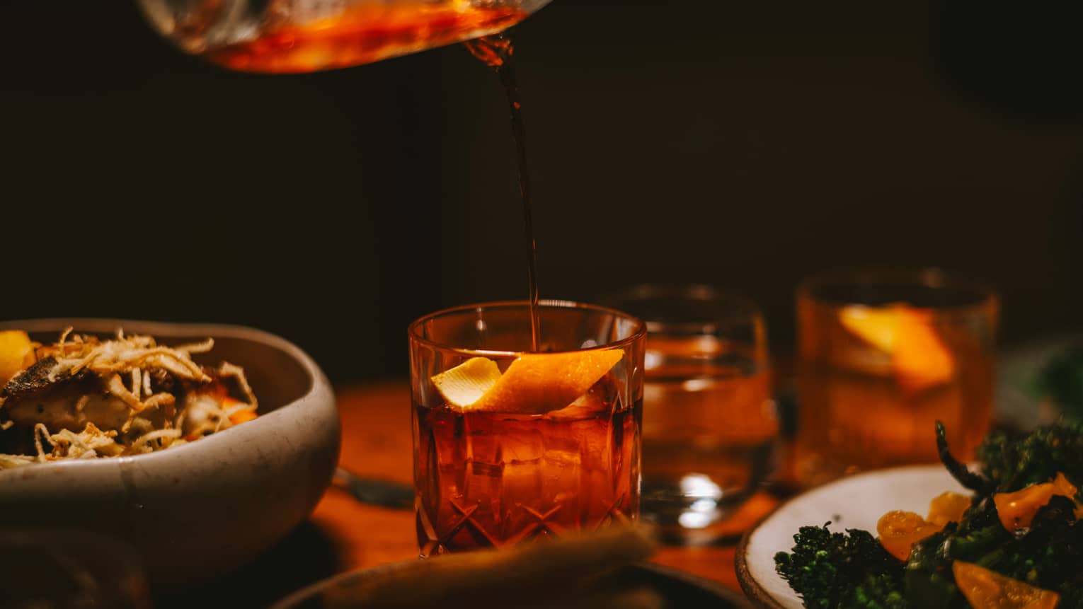 Pouring a drink into a glass with an orange slice.