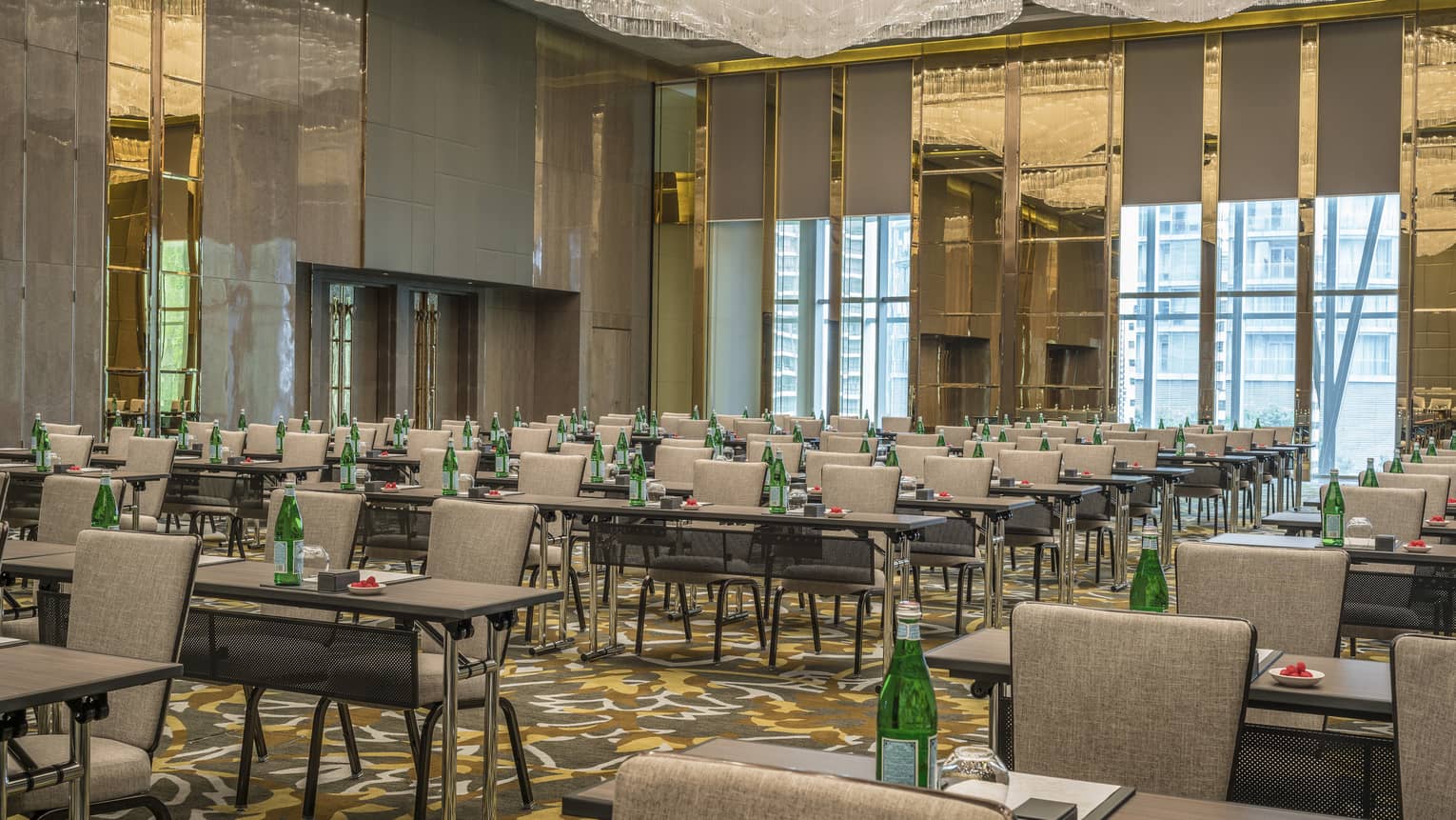 Rows of meeting tables with green water bottles in conference set up in ballroom