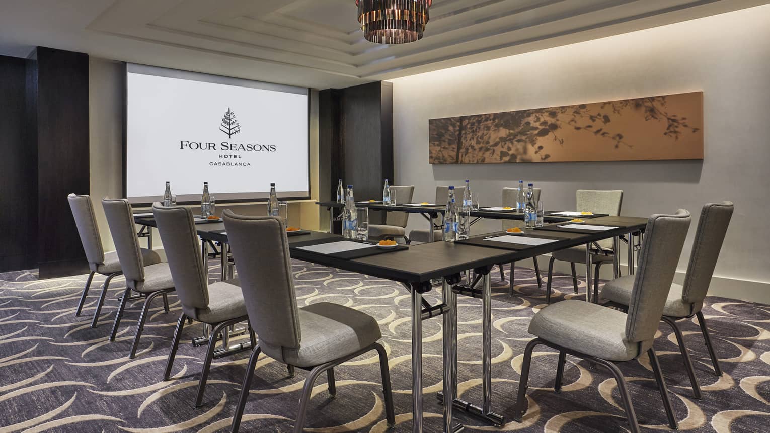 Business meeting room with large screen with Four Seasons logo, tables and chairs