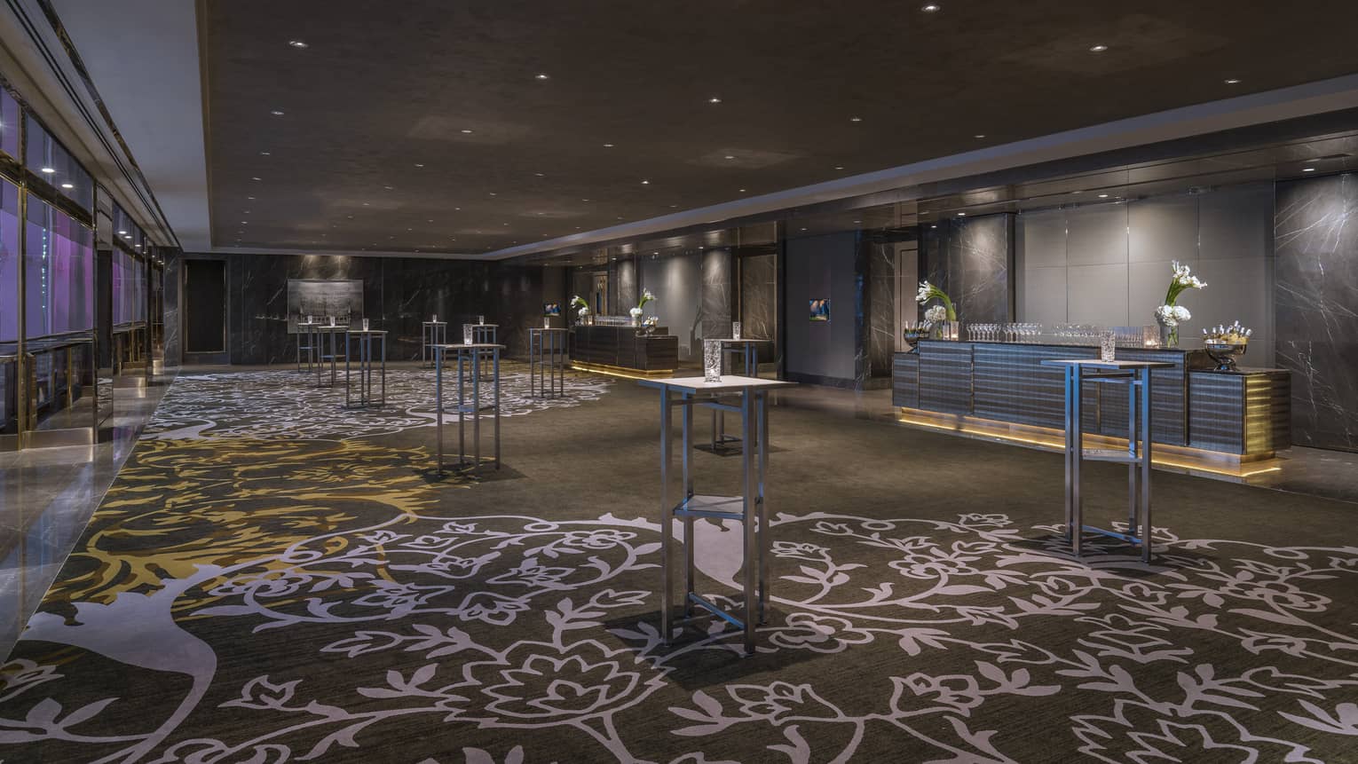 Empty pre-function area with small cocktail tables on patterned carpet