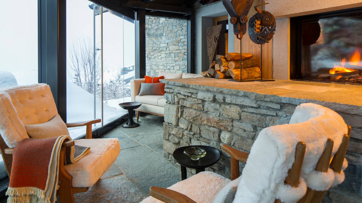 Cigar Room plush white lounge chairs by stone ledge with logs, sculptures, gas fireplace