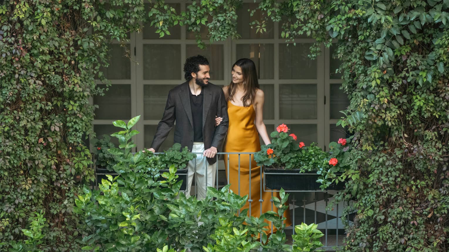 Two guests look out upon a greenery-filled outdoor space.