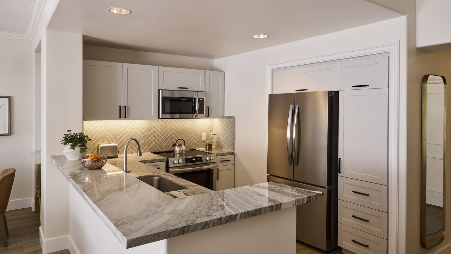 Sleek kitchen in private villa, featuring stainless steel appliances and chevron backsplash