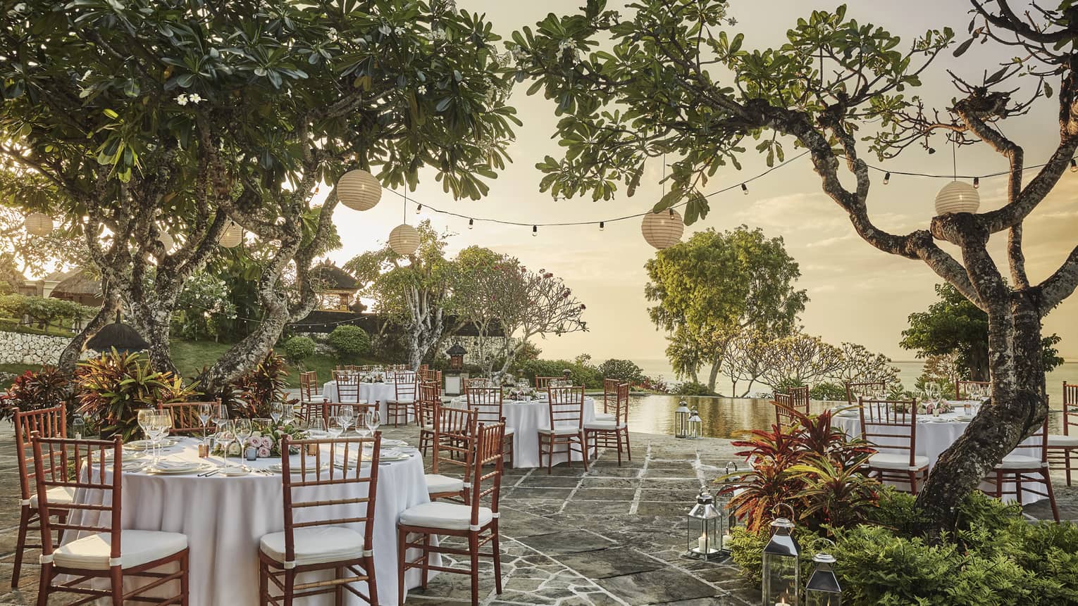 Patio wedding reception at sunset, small round banquet tables and chairs under trees