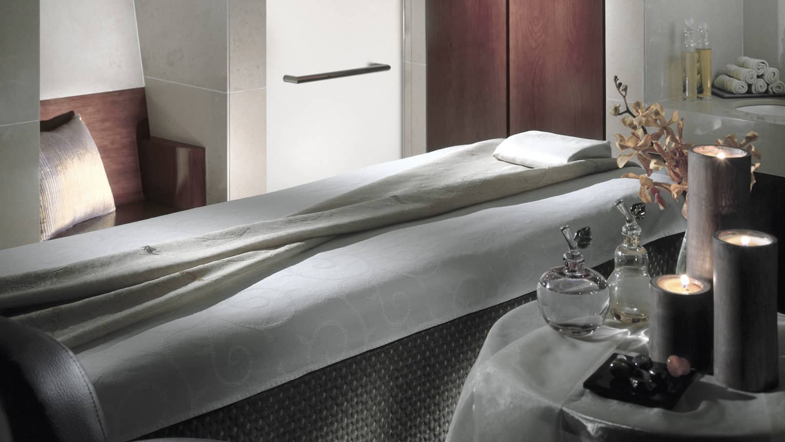 Massage bed in spa next to table with oils, candles
