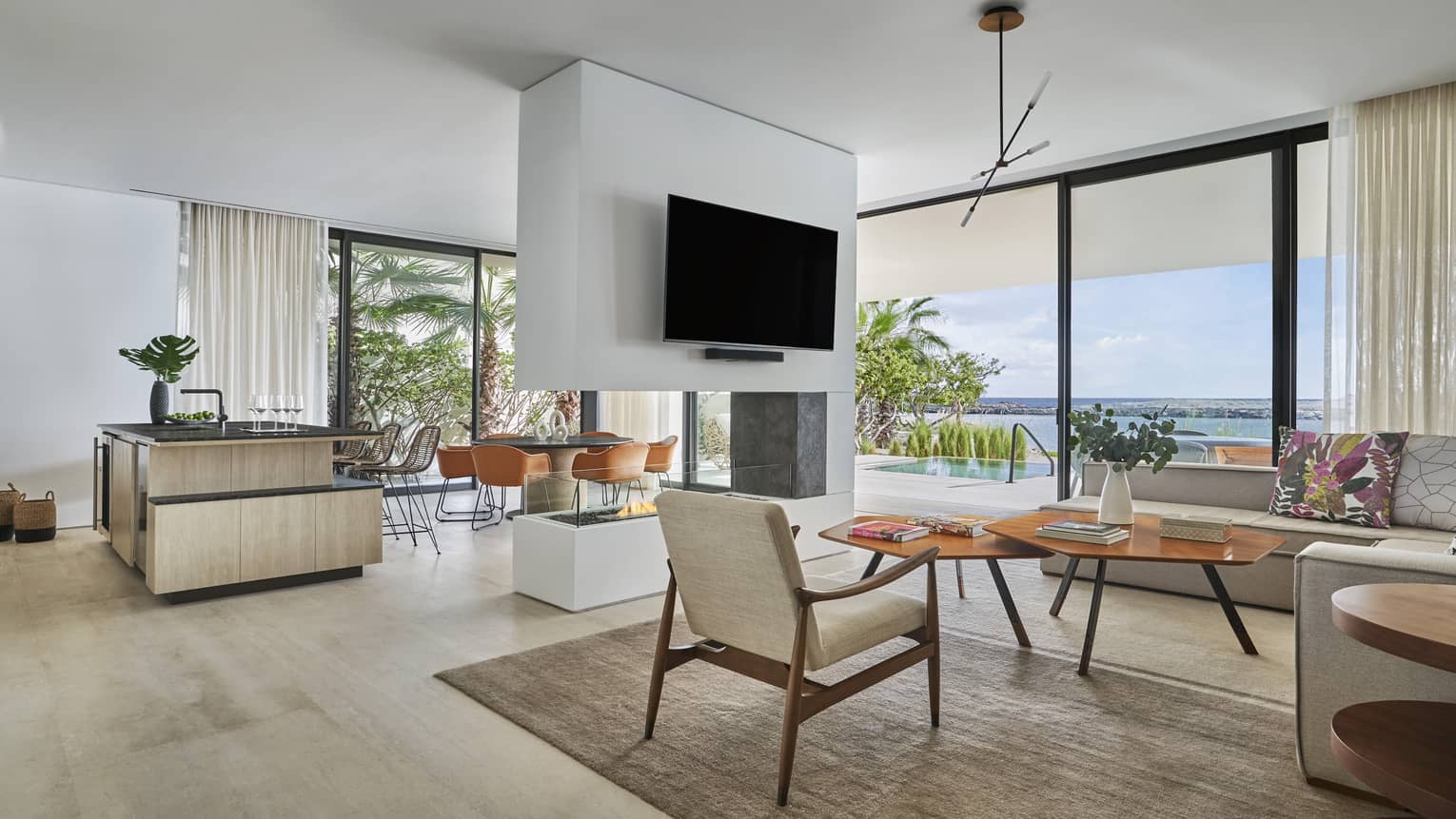 Open-concept living room, kitchen and dining room with modern fireplace in the middle