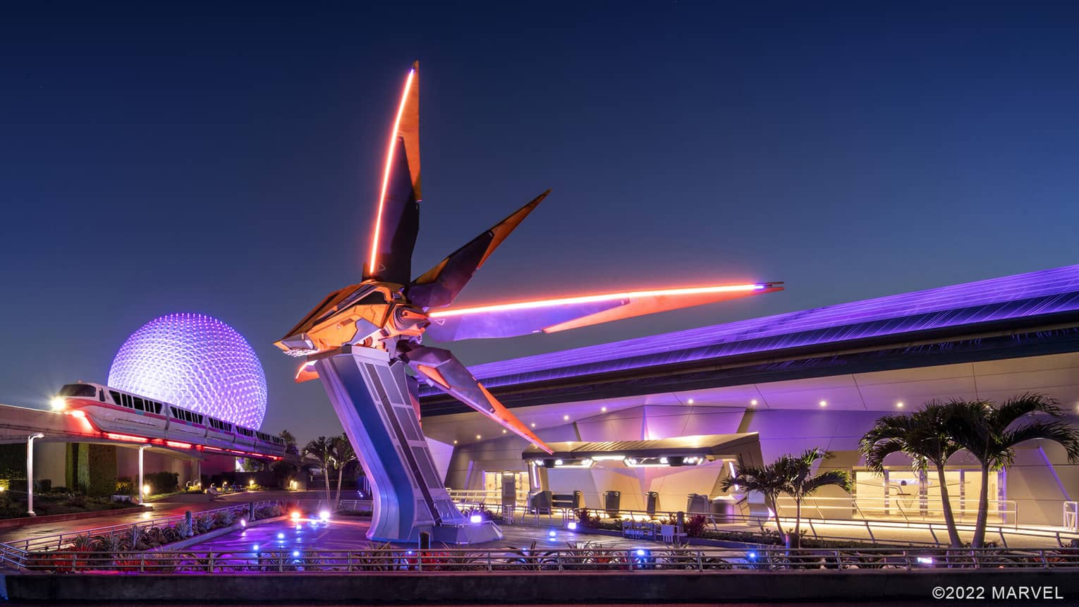An orange and black sci-fi spaceship resting on a tall pedestal with a tram moving near it.
