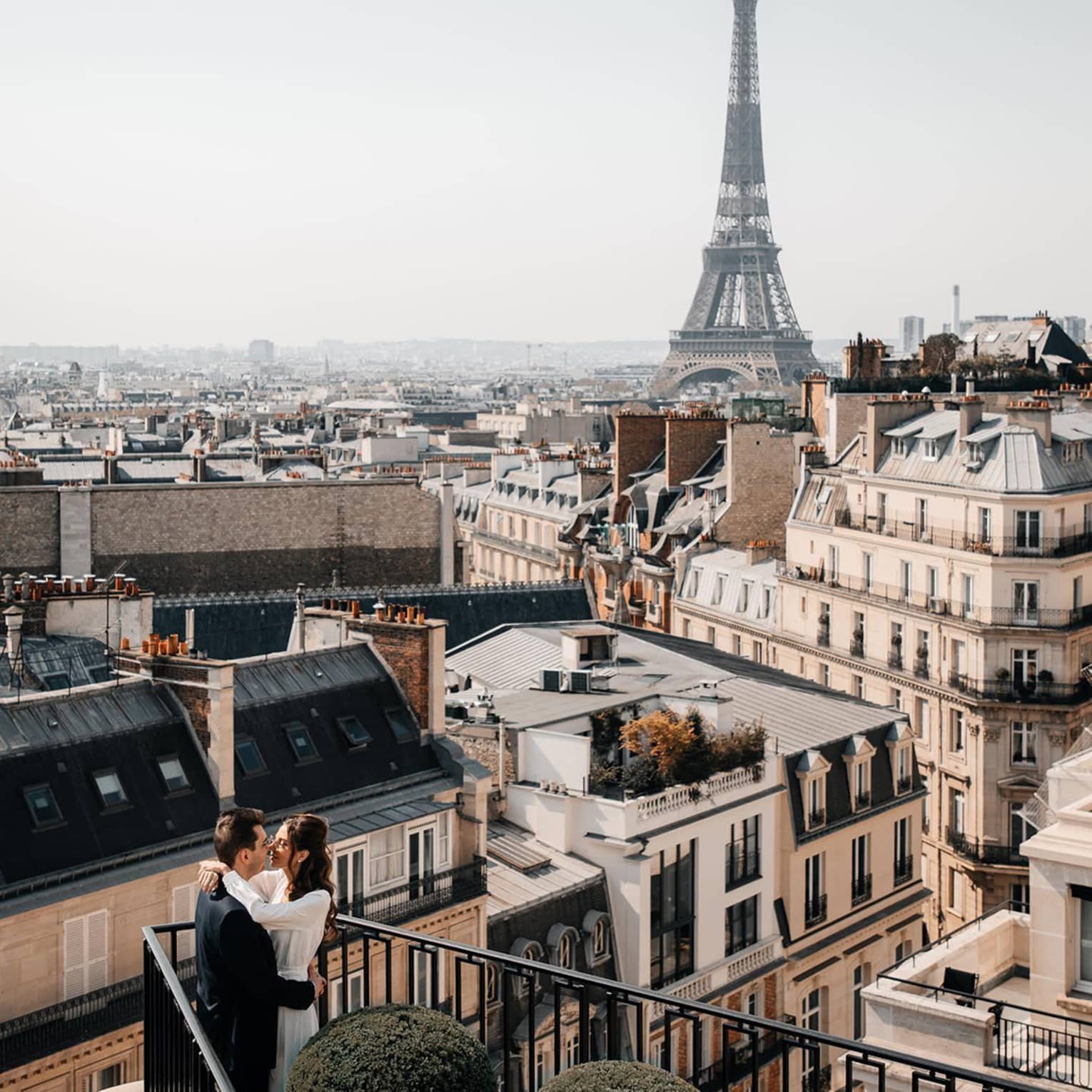 Couple embracing on Paris Hotel terrace with Eiffel Tower view