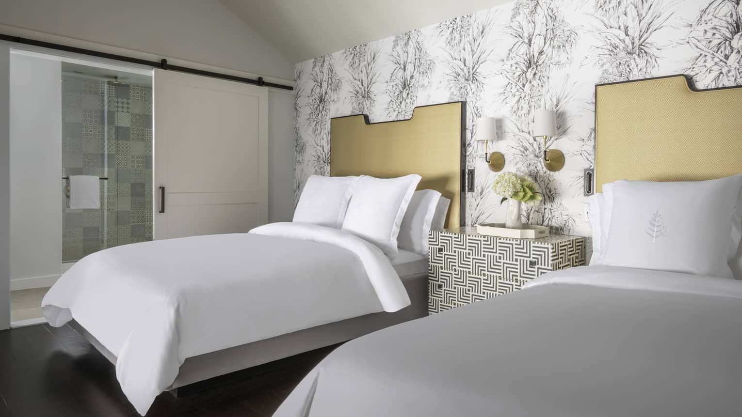 Resort room with two double beds, patterned wallpaper and a decorative nightstand