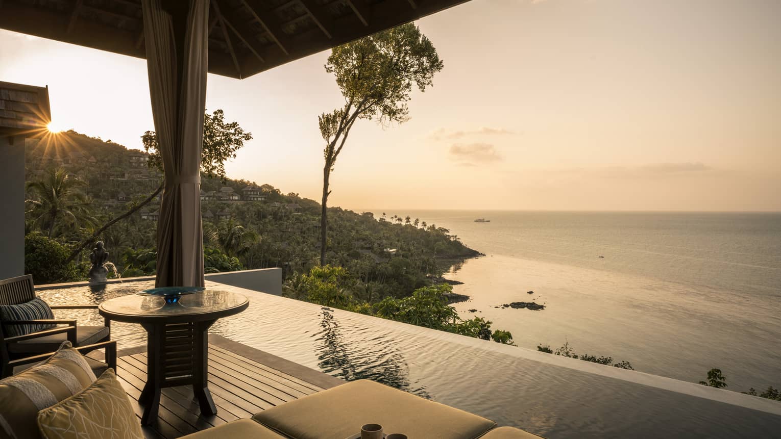 One-bedroom pool villa patio chair, infinity pool overlooking mountain, ocean at sunset