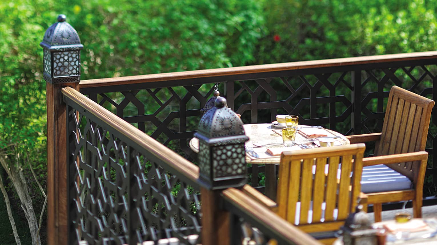 Close-up of small lanterns on wood corner balcony by small cafe table