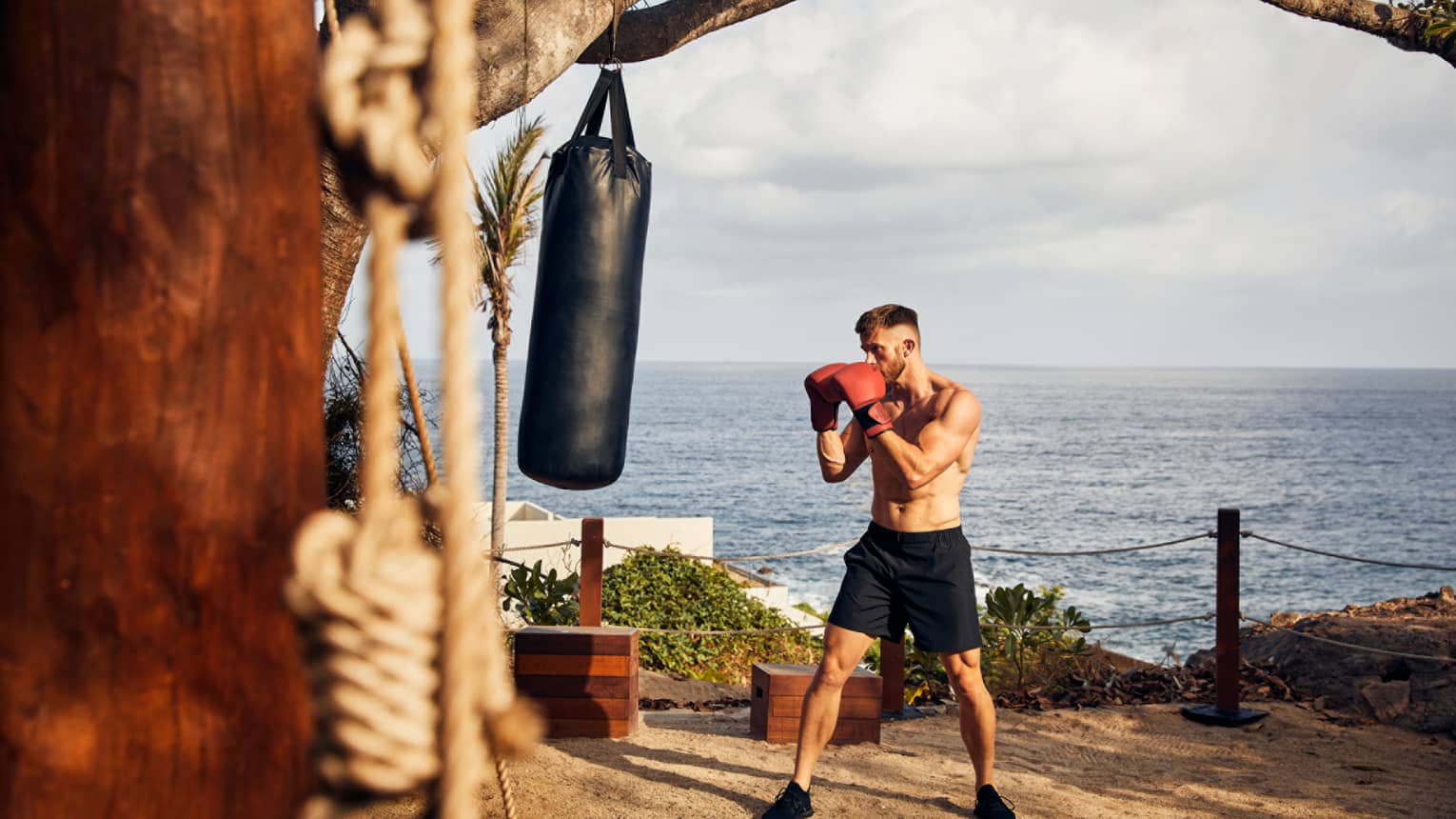 A guest engaged in a boxing session, perched above a cliff overlooking the Pacific Ocean