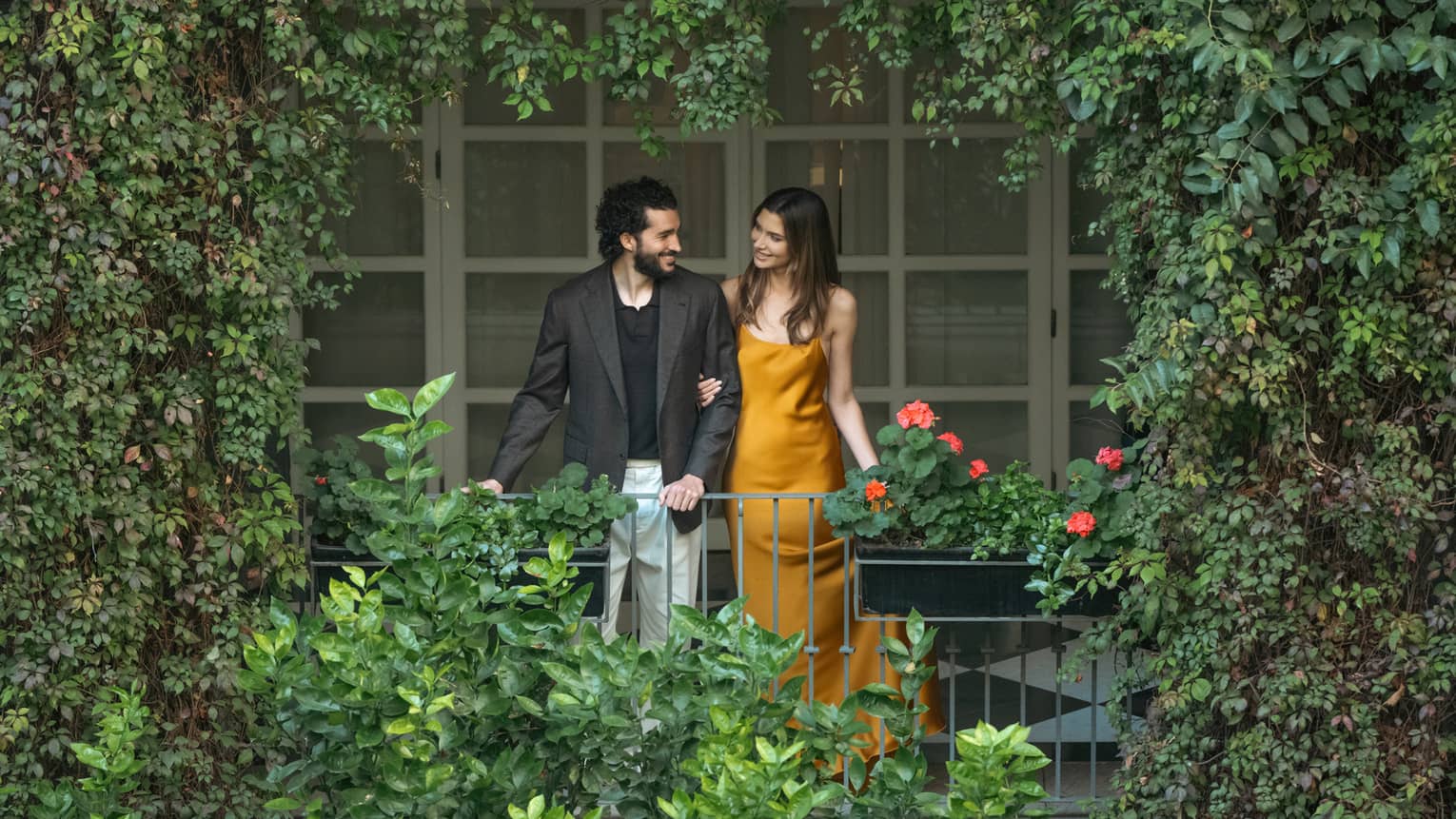 Two guests look out upon a greenery-filled outdoor space.