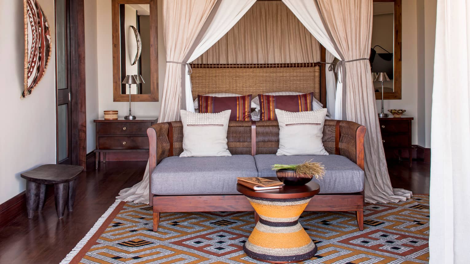 Savannah Room poster bed and canopy behind wicker loveseat, small table