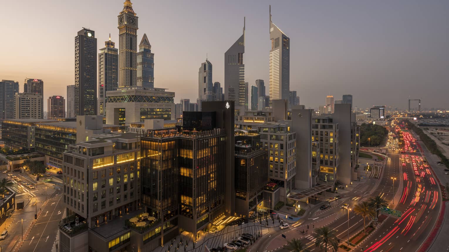 Aerial view of Dubai city skyline, road, lights around Four Seasons International Financial Centre hotel at sunset