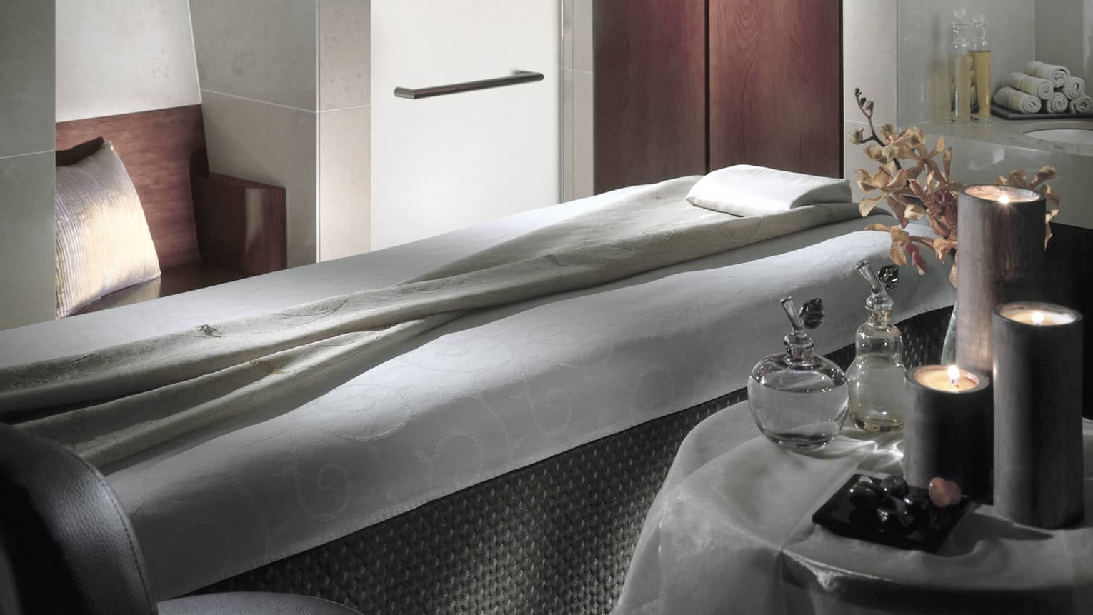 Massage bed in spa next to table with oils, candles
