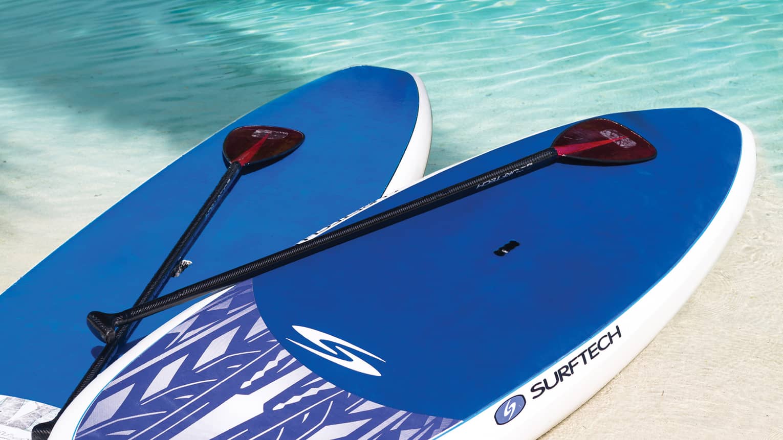 Close-up of two blue stand-up paddleboards and paddles