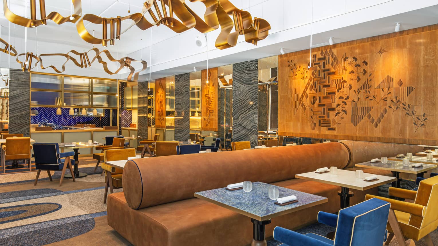 Modern dining area with gold, blue and deep camel accents and art flanking walls and ceiling