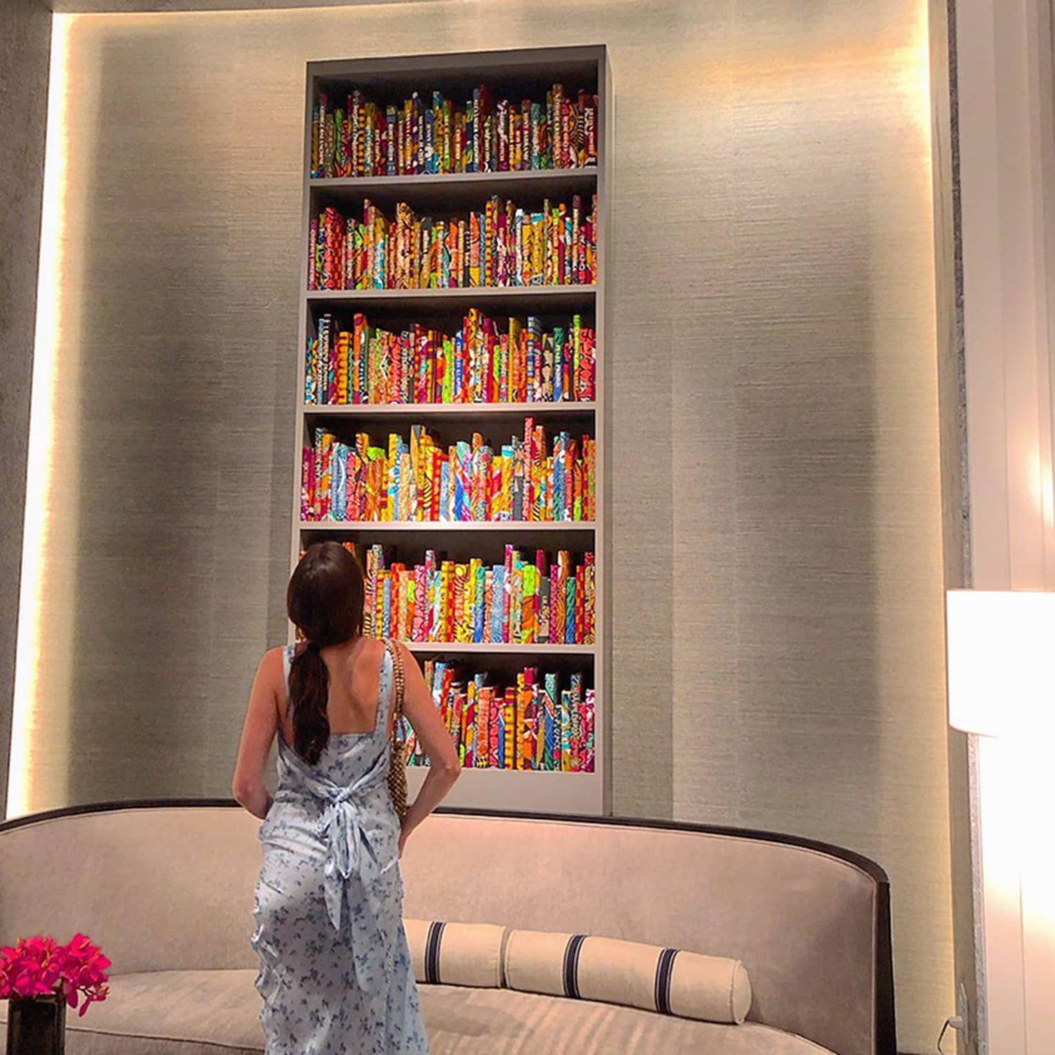 A girl glances up at a floor to ceiling bookshelf