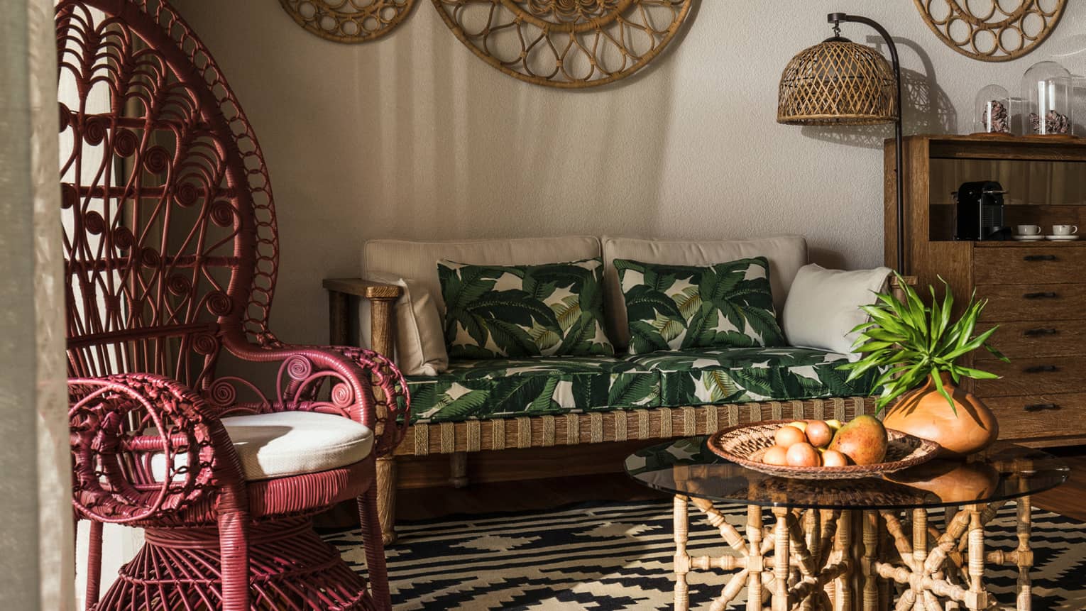 Close-up of decorative red wicker chair with tall back and white cushion, wicker sofa with palm pillows