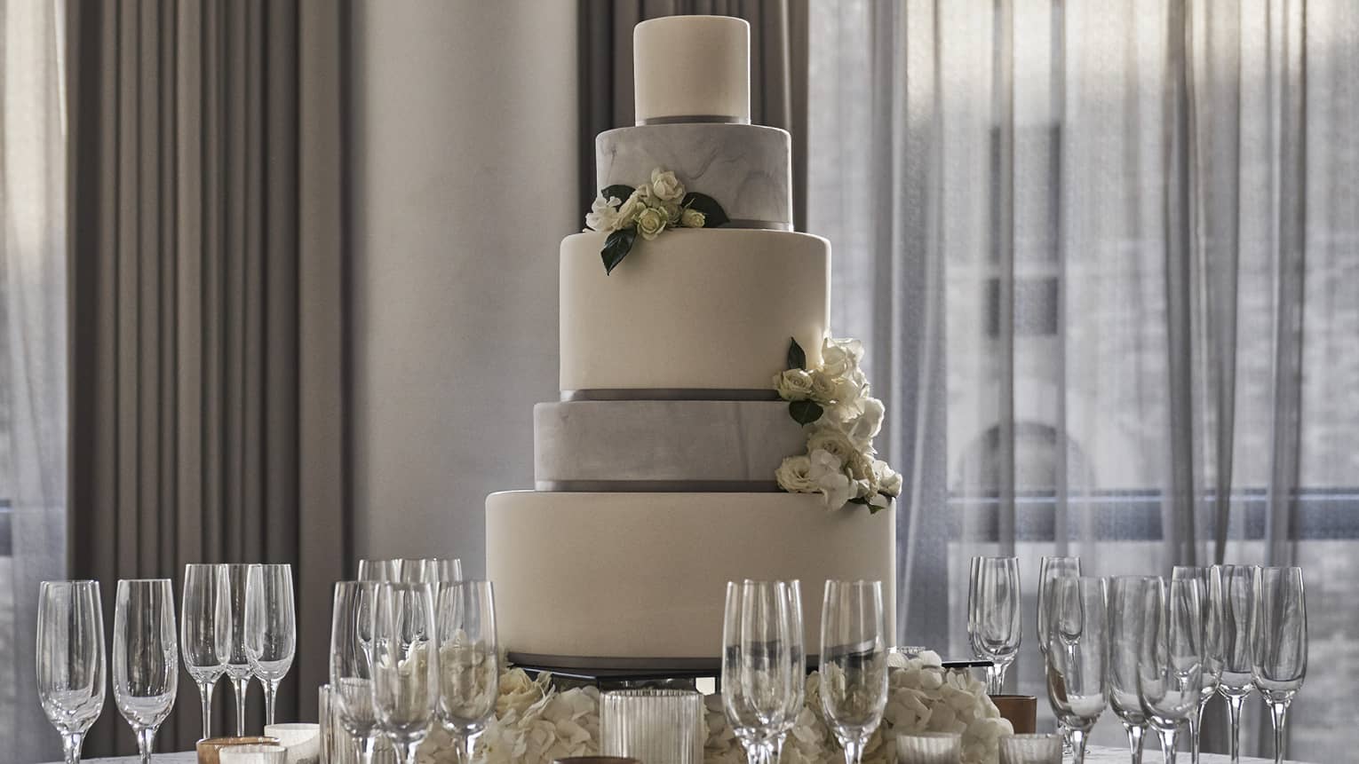 Tiered wedding cake on round banquet table with Champagne glasses