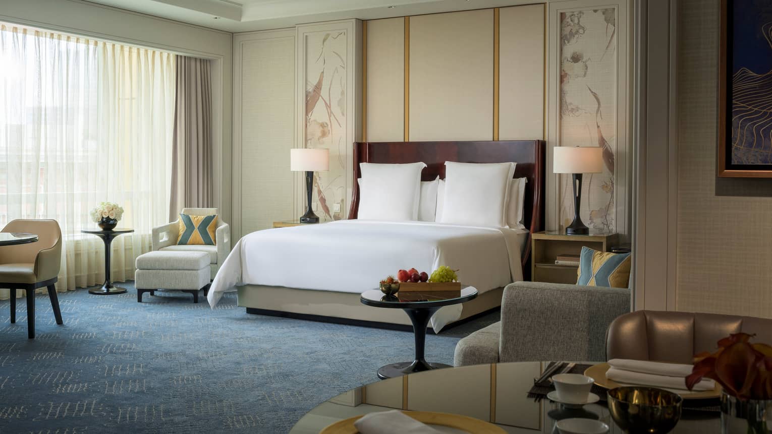Premier Room hotel bed with white linens against wall with decorative panels, armchair by window
