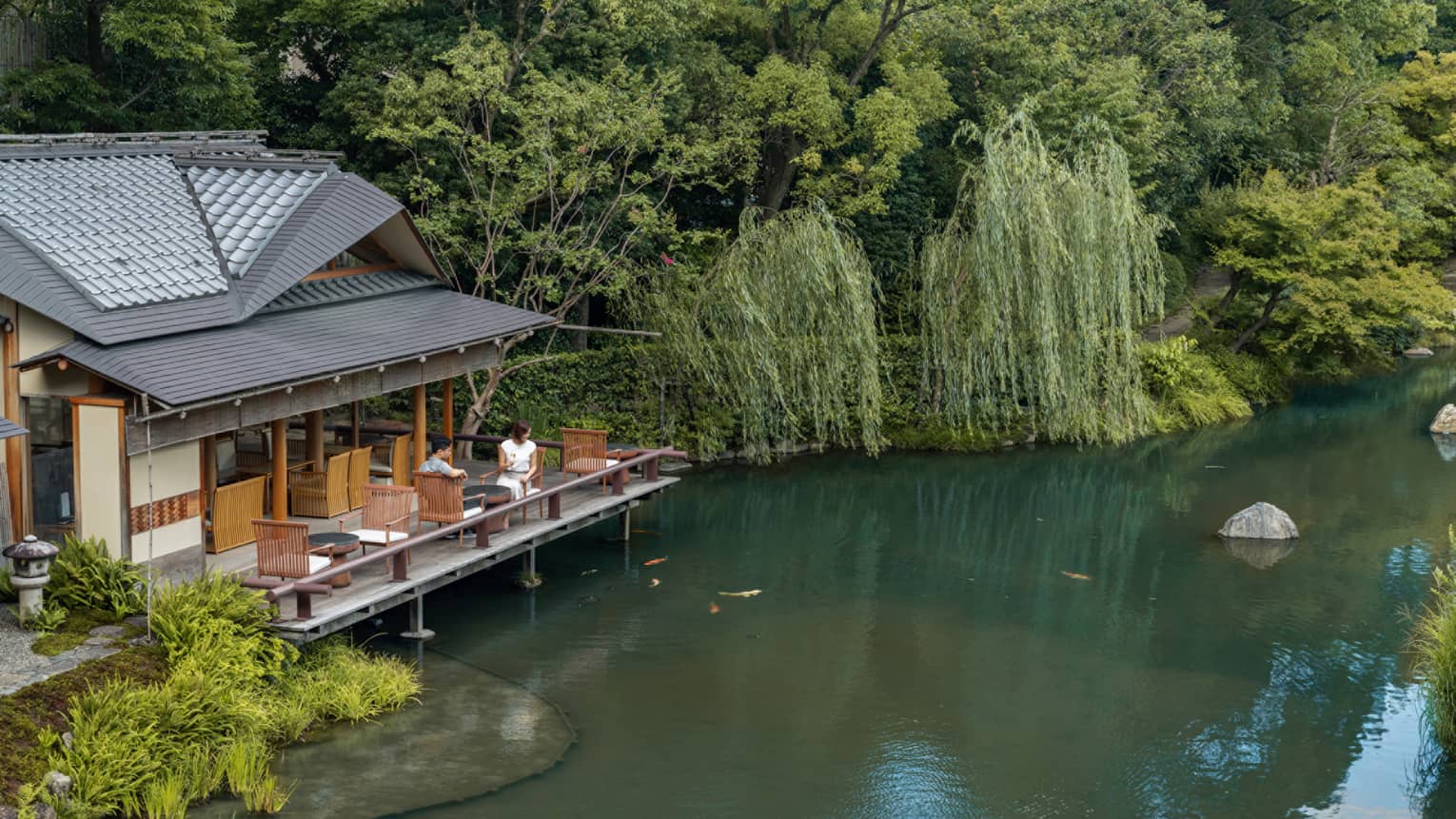 Two guests sit on the outdoor terrace of a pagoda overlooking the koi pond