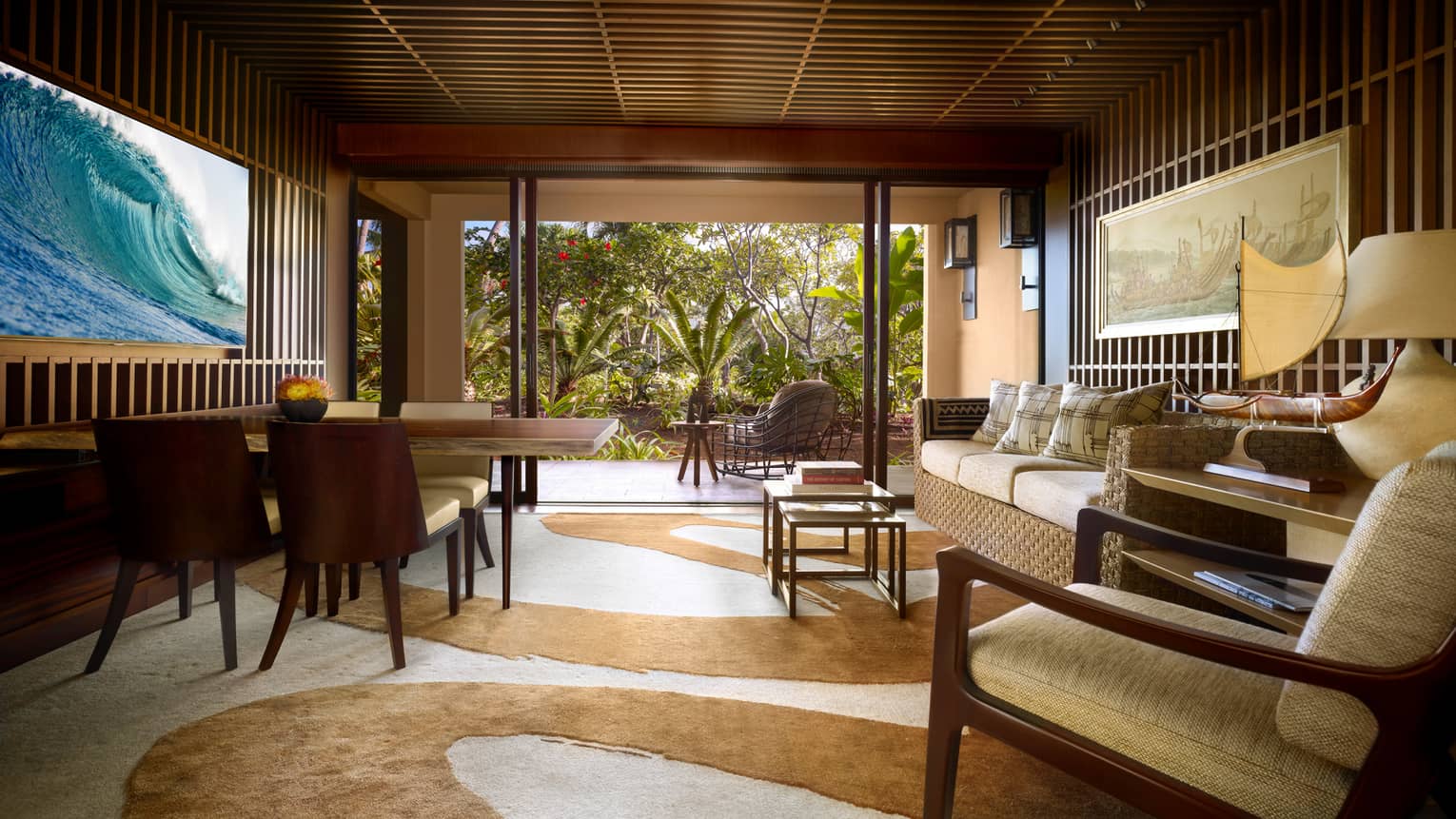 Ohana Garden-View Suite teak-panelled walls, wave screen over wood dining table, sofa, swirl-patterned carpet