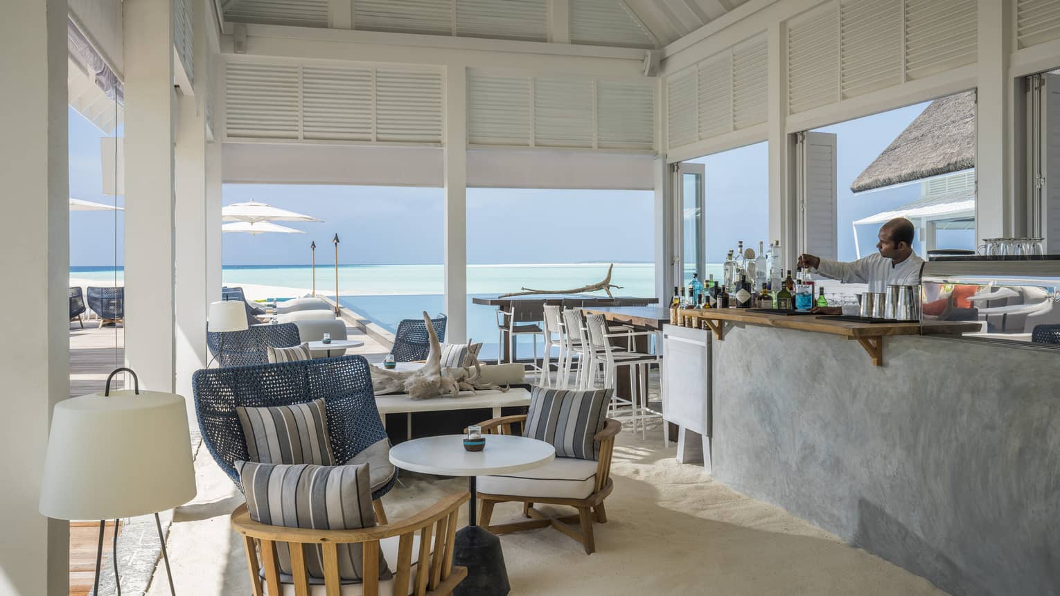 A comfortable, oceanside bar at the Blu Beach Club with plush chairs and a variety of cocktail selections