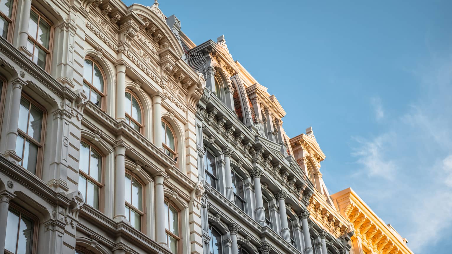 Close-up of ornate historic building facade with arched windows and decorative columns under a clear blue sky