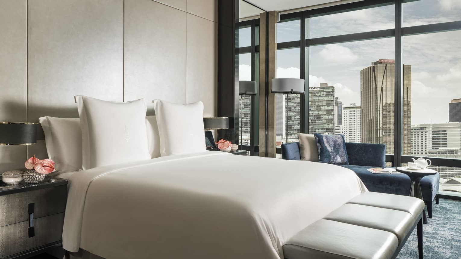 Bed and leather bench in front of padded wall, floor-to-ceiling wall of windows