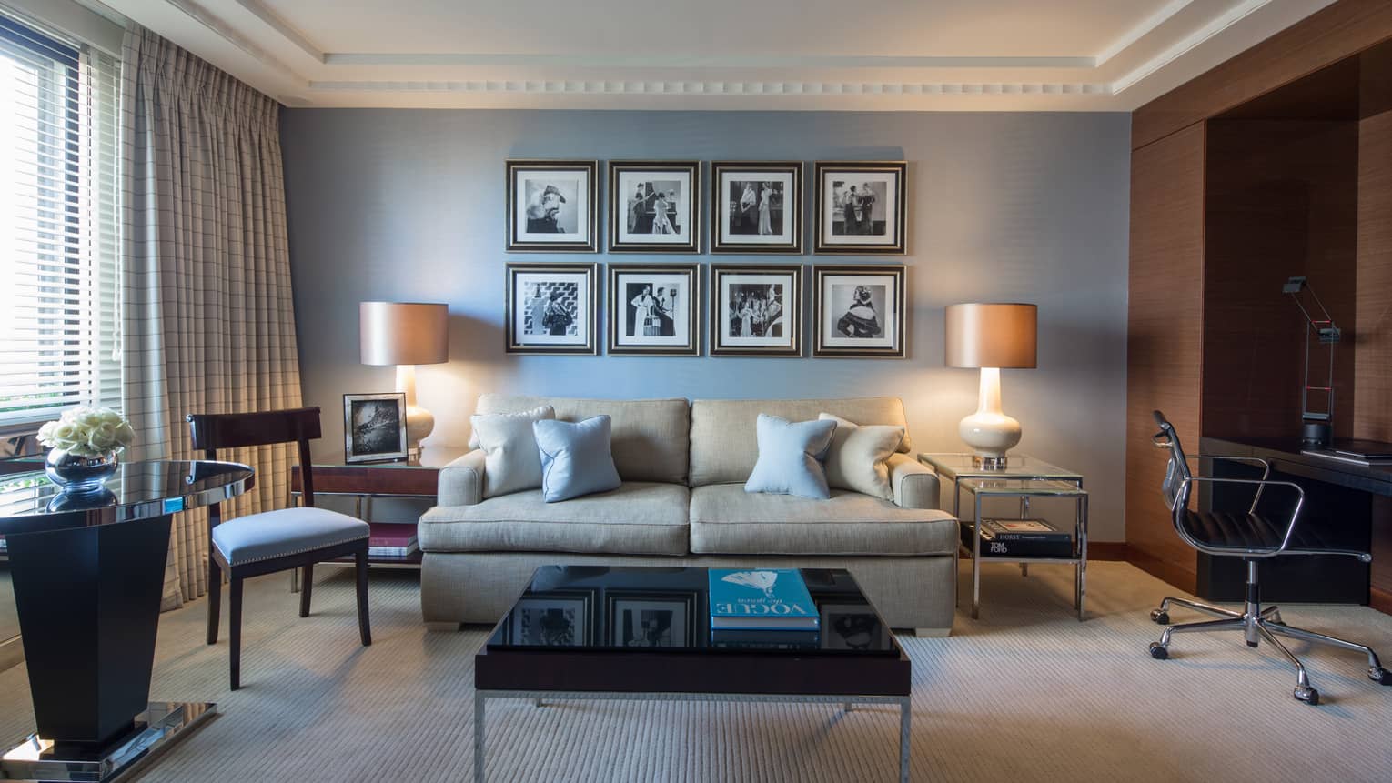 Living room with square coffee table, tan sofa, and blue wall with picture gallery
