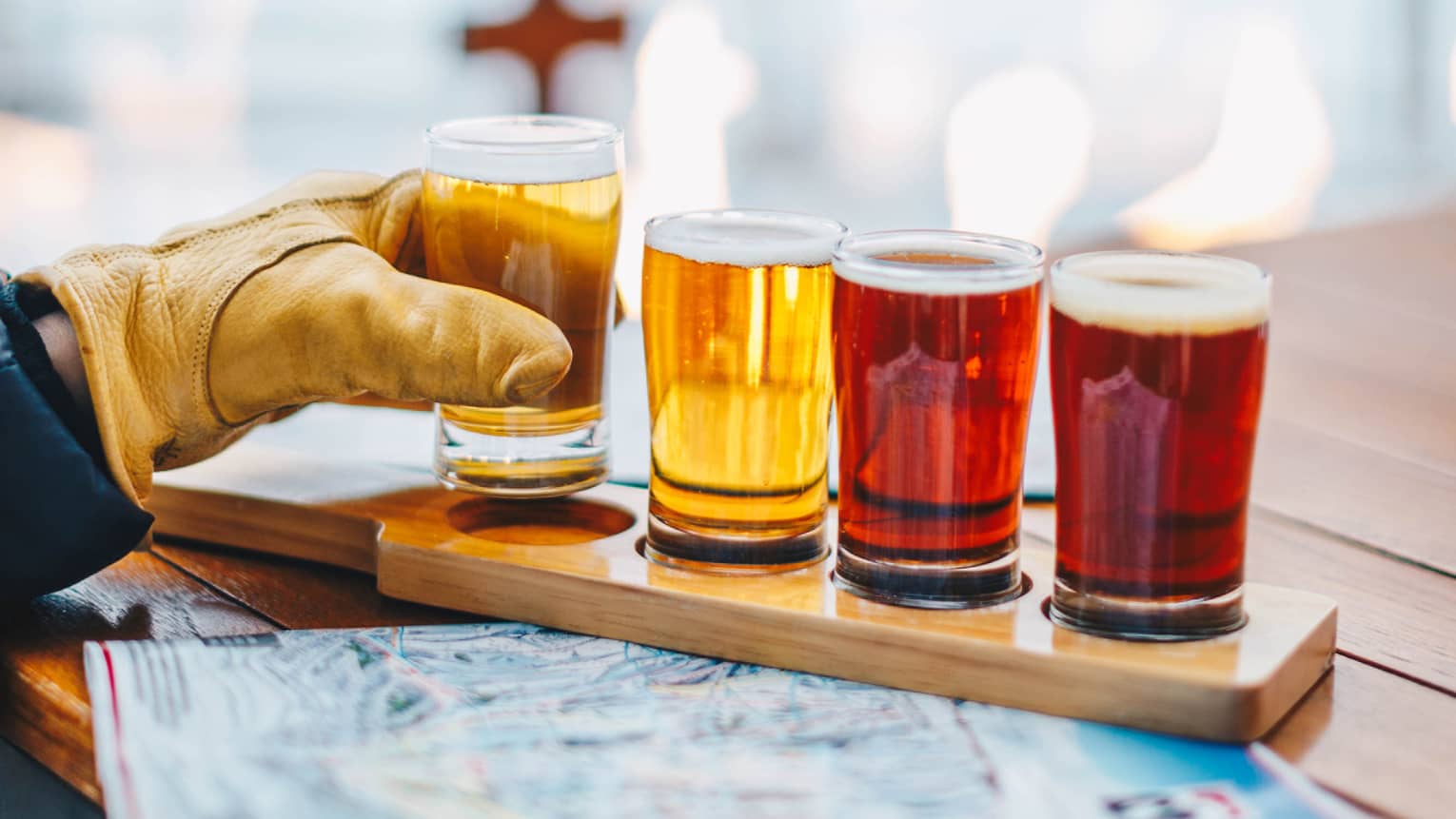 Three drinking glasses set on a table, a person reaching for one of them