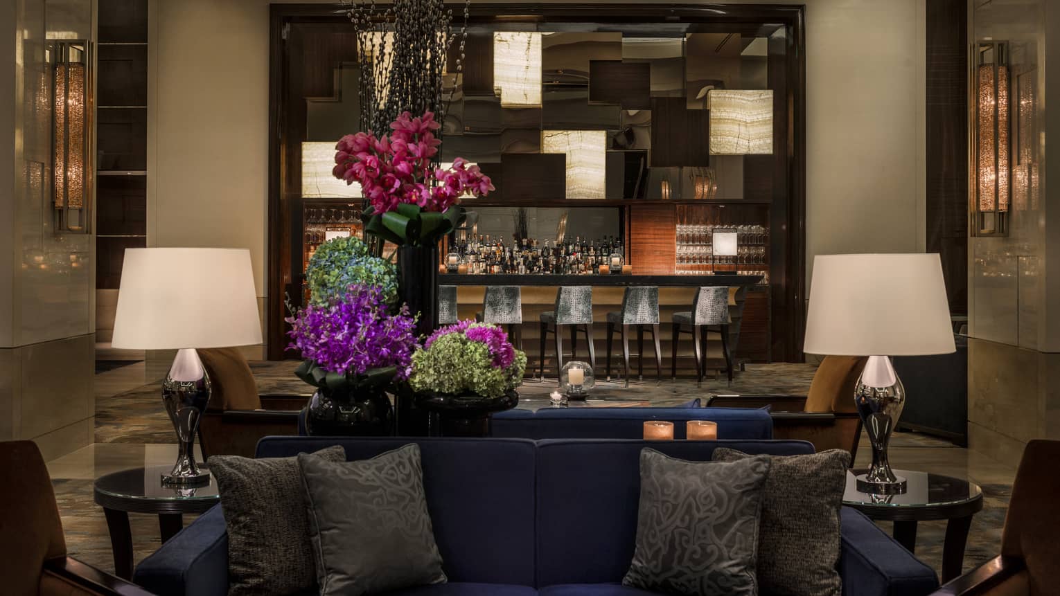Opus Bar with grey stools behind lounge sofas, purple flowers
